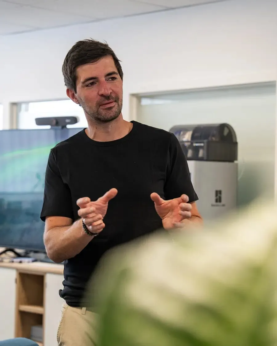 Stephan erklärt mit beiden Händen etwas, im schwarzen T-Shirt in einem hellen Raum